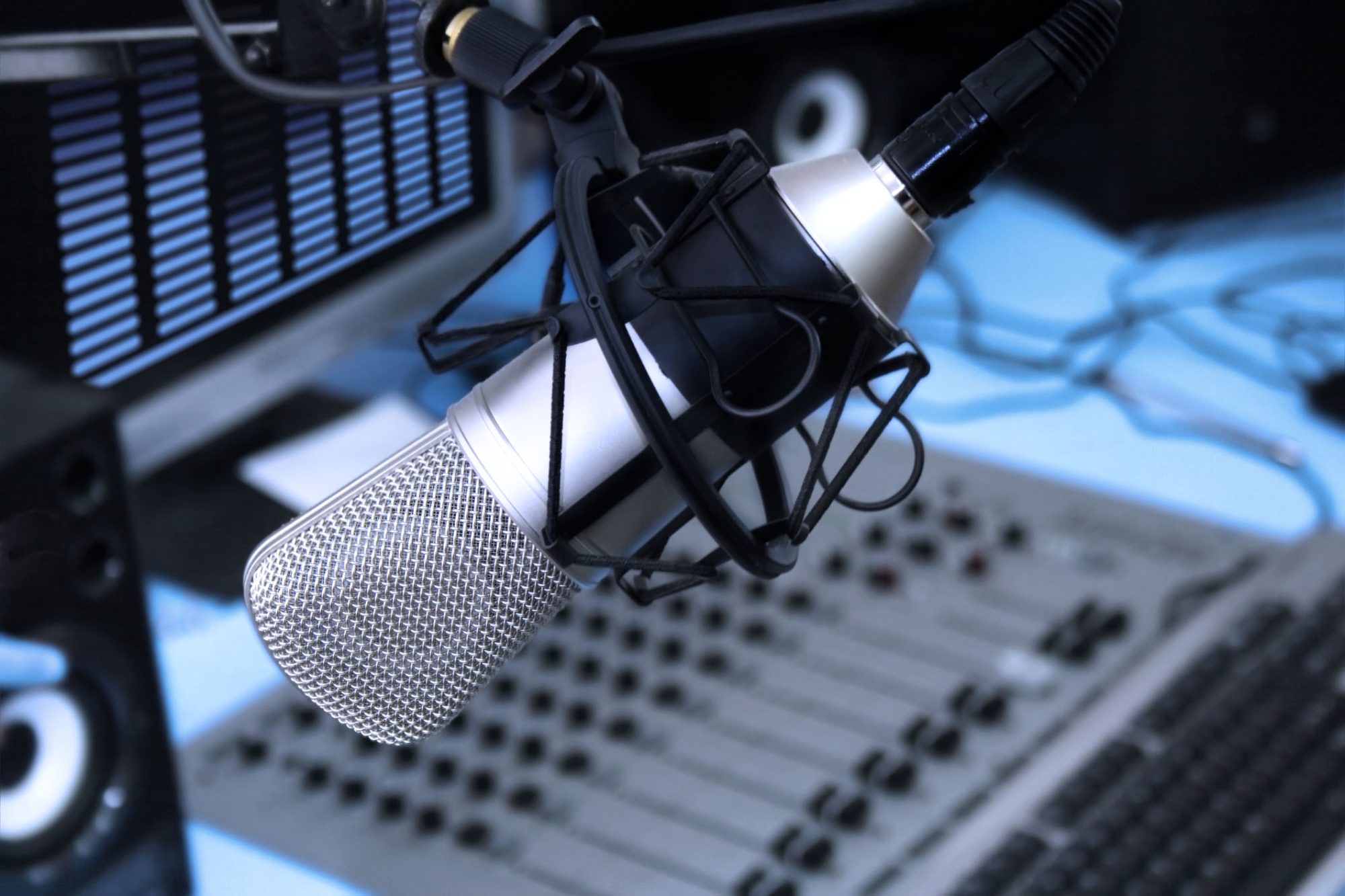 In radio studio. A mic in front of the control panel in broadcasting studio